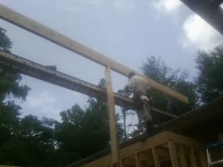 Carpenter setting a ridge beam over a new addition frame — Ice Dam Removal by Roofing Brothers in Rosharon