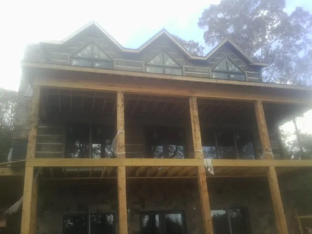 Dormers and porch framing on a large log home under construction — Roof Coating work by our crew in Rosharon
