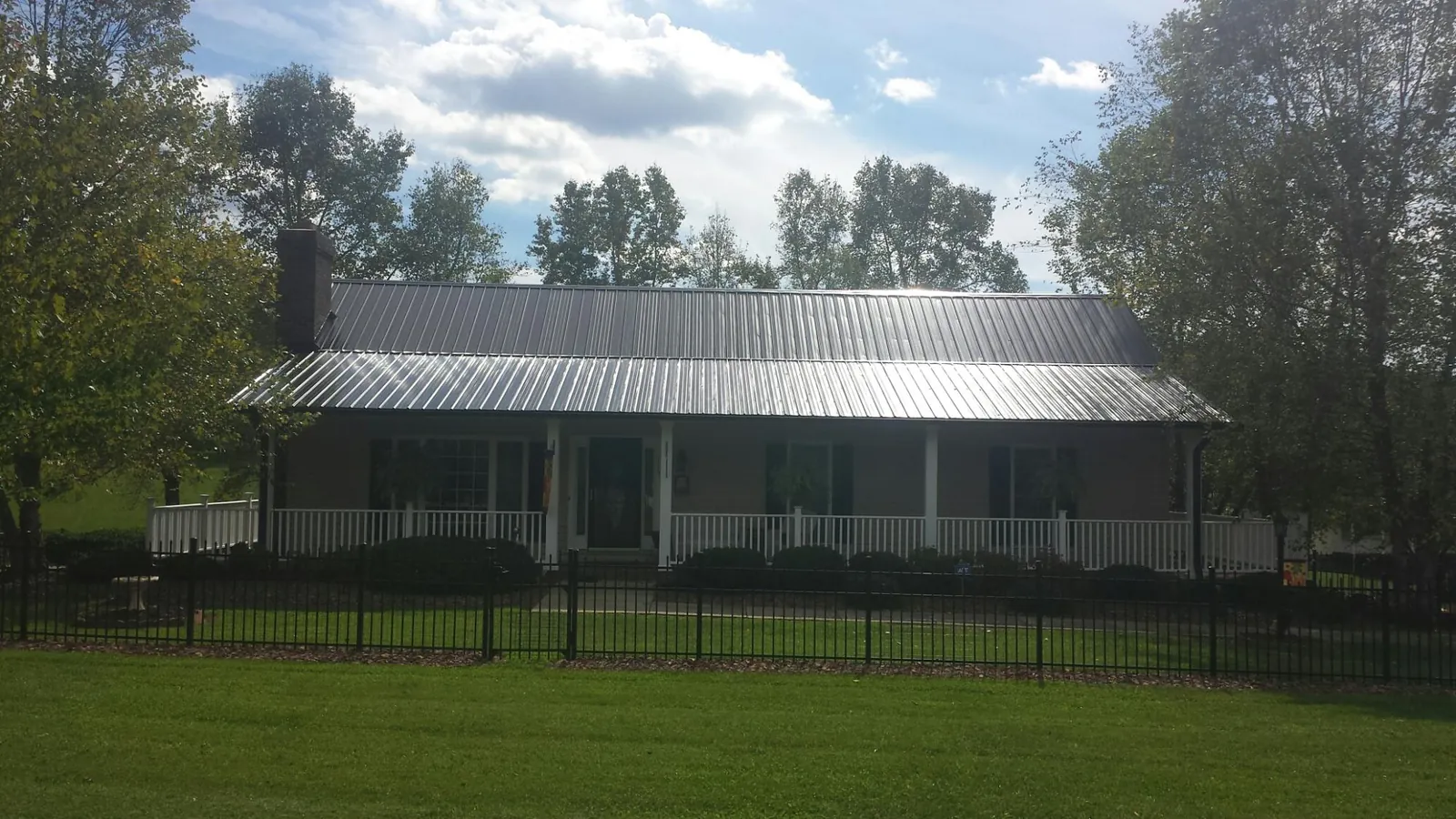 Gray metal roof on a brick ranch with a full width front porch — Gutter Guard Installation work by our crew in Rosharon