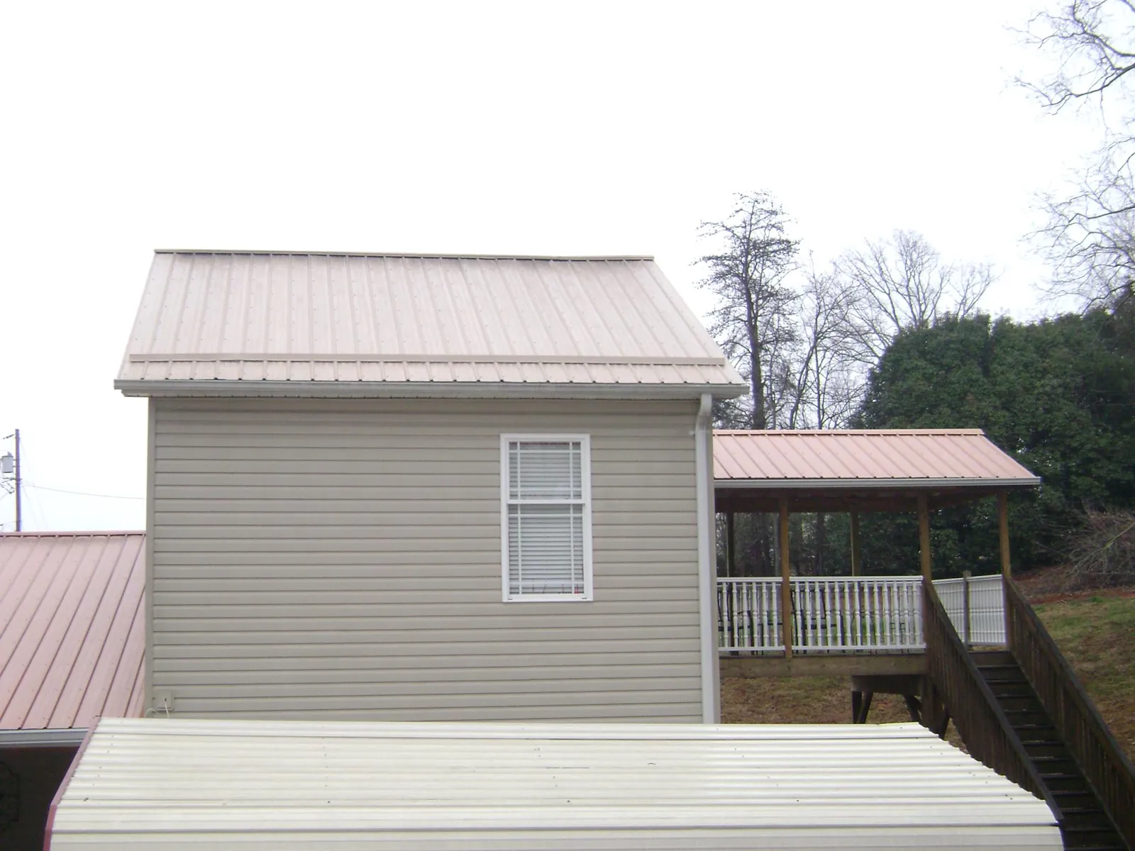 Tan metal roofs on a two story addition and attached porch, from a Roof Replacement job in Rosharon